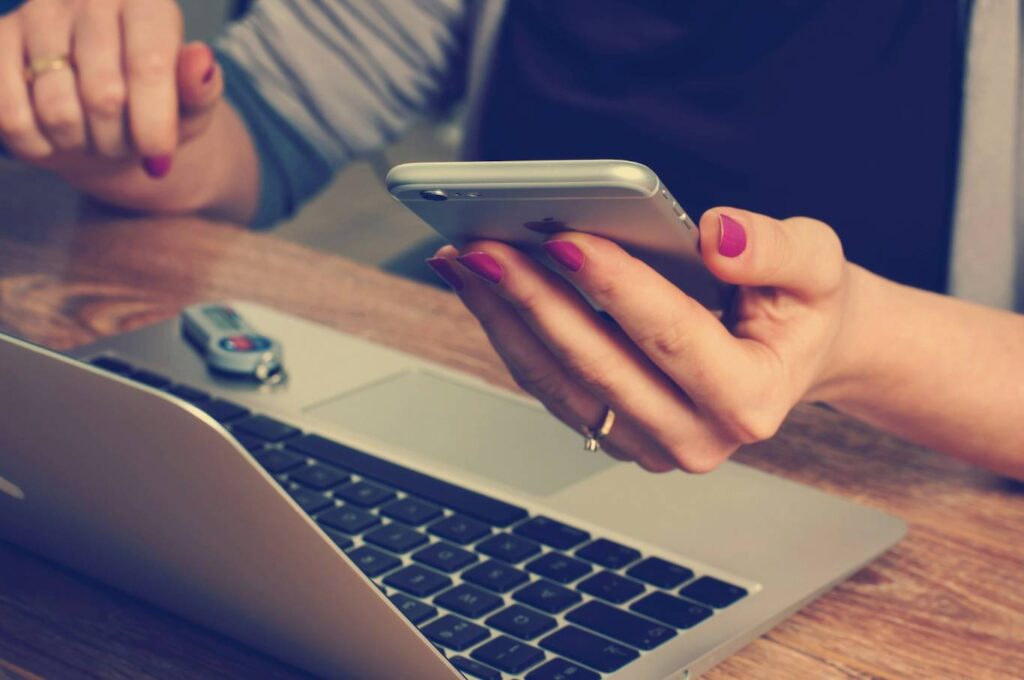 woman holding a phone in front of laptop