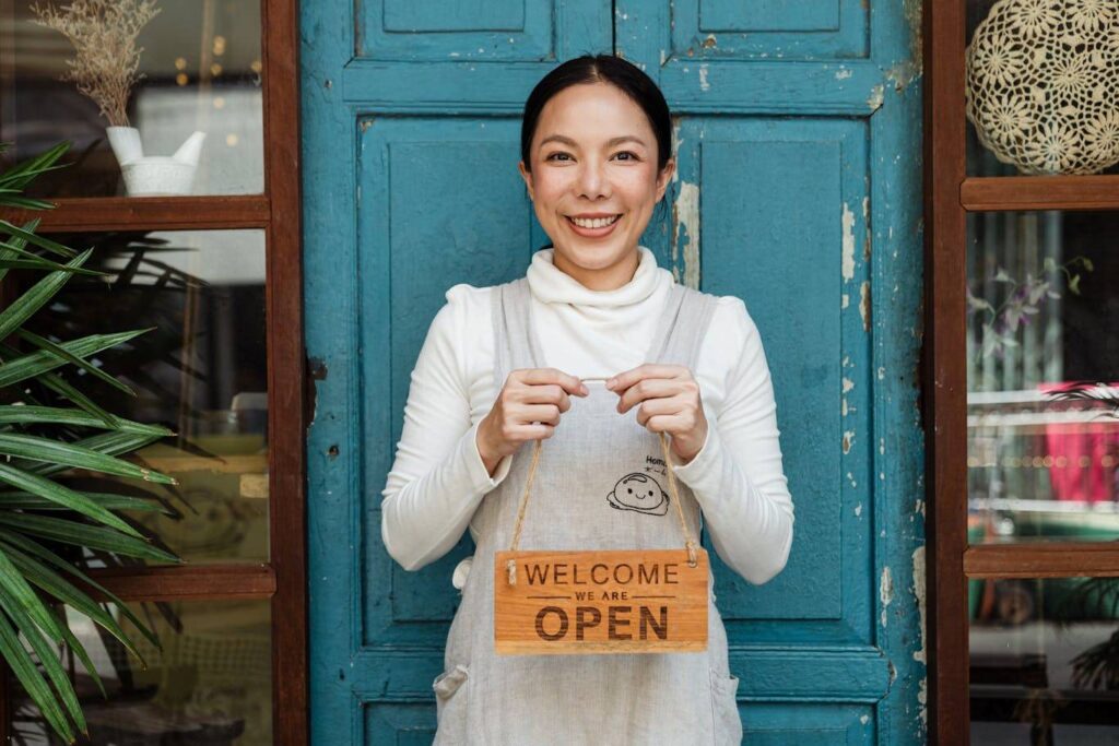 Small businesswoman in apron wearing an open sign