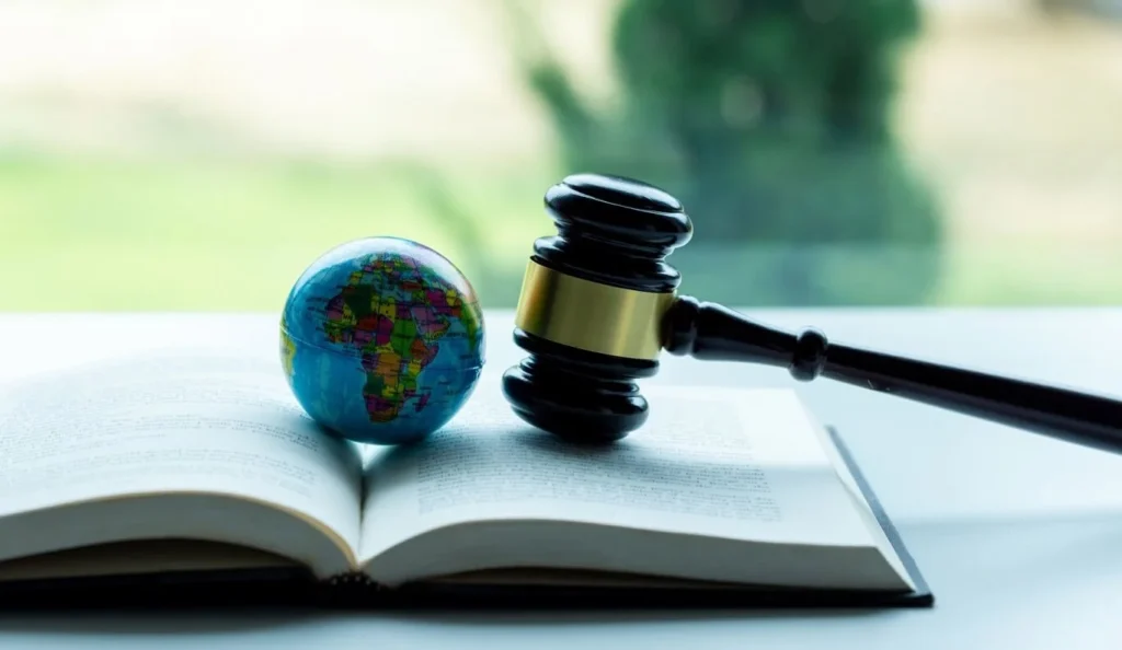 Concept of International Legal Framework: Globe and gavel on top of an opened book. 