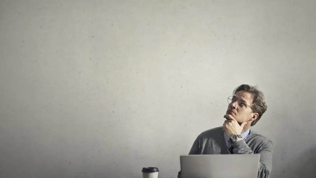 Man weighing the pros and cons of electronic signature while working on laptop.