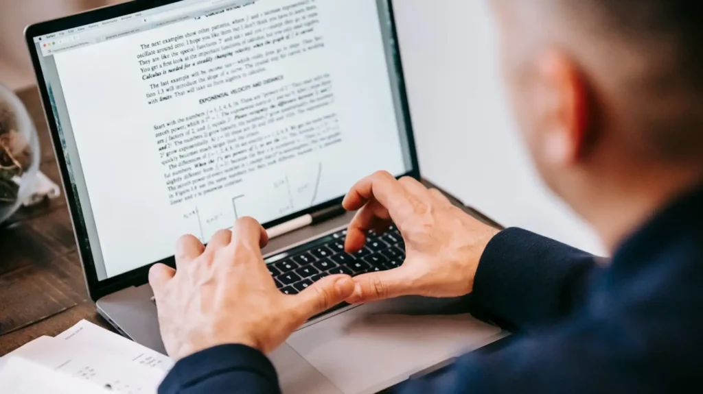 Man reading a contract on his laptop before signing.