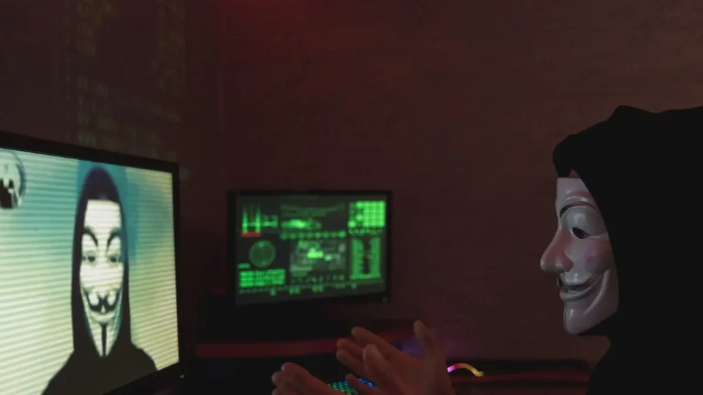 Concept of online security: Person in anonymous mask at computer desk